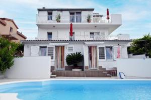 a white house with a swimming pool in front of it at Apartments MajaPaula in Slatine