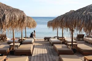 a beach with chairs and straw umbrellas and the ocean at Alimos House in Athens