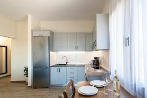 una cucina con mobili bianchi e un tavolo con sedie di Bens Apartments-One Bedroom Premium Apartment ad Agia Paraskevi
