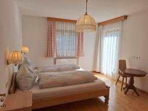 1 dormitorio con cama, mesa y ventanas en Apartments Insam en Santa Cristina in Val Gardena