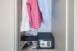 un armadio con uno scaffale con un orologio e vestiti di Bens Apartments-One Bedroom Premium Apartment ad Agia Paraskevi