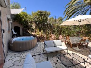 a patio with a hot tub and chairs and an umbrella at SIMONE, Appartement maison, quartier calme, grande terrasse, SPA, barbecue, 2 chambres in Fréjus