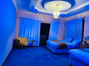 een blauwe kamer met een bed en een stoel bij GoldenWays Motel in Mbabane