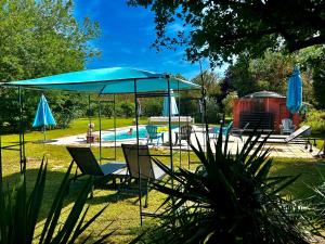 un patio con una sombrilla y sillas azules y una piscina en Domaine Plan des Devens, en Roussillon