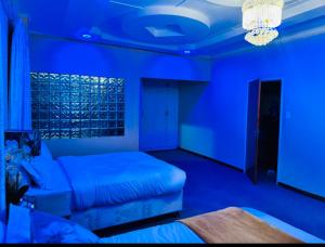 Habitación azul con cama y sofá en GoldenWays Motel en Mbabane