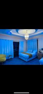 Dormitorio azul con cama y lámpara de araña en GoldenWays Motel en Mbabane