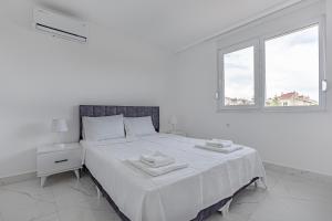 a white bedroom with a bed with two towels on it at NEAR BY THE LAND OF LEGENDs , PRİVATE POOL , VİLLA LARİSA in Belek +23 photos