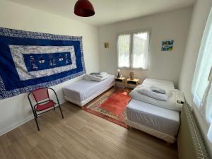 a bedroom with two beds and a red chair at La Villa de la plage in Angoulins