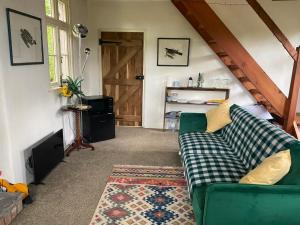 een woonkamer met een groene bank en een deur bij Wye Riverside Lodge in Llandrindod Wells
