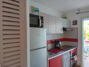 a kitchen with a white refrigerator and a microwave at Au bout du rêve - Le Gosier in Le Gosier
