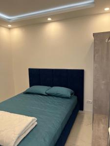 a bed with a blue headboard in a room at Vip apartmani in Tivat