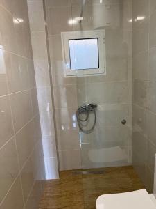 a bathroom with a shower with a window and a toilet at Vip apartmani in Tivat +2 photos