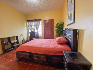 um quarto com uma cama com um edredão vermelho em El Jardín de Banu em Magdalena Milpas Altas