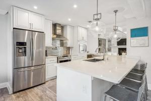 a kitchen with white cabinets and a stainless steel refrigerator at Stunning Townhouse w Tennis & Pool in Southampton