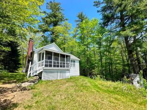 a white house on a hill in the woods at 11G Quintessential New Engalnd Cottage with Fantastic Views! in Sugar Hill