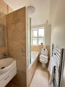 a bathroom with a sink and a toilet and a tub at Hyde Park Beautiful Apartment in London