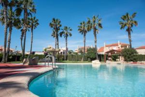 a swimming pool with palm trees in a resort at El Olivo and Brisas Beach house in Gran Alacant