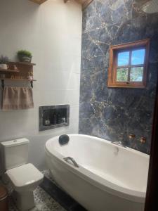 a bathroom with a white tub and a toilet at Pousada Villa Del Bosque in Monte Verde