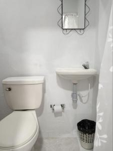 a white bathroom with a toilet and a sink at Hotel Candilejas Serenity in Barrancabermeja