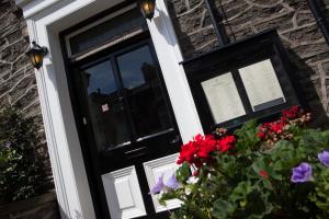 una puerta negra con flores delante de una casa de ladrillo en The Lamplighter Dining ~ Rooms, en Windermere