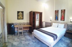 a bedroom with a bed and a desk and a table at Canggu Pinpoint Rooms in Canggu