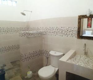 a bathroom with a toilet and a sink and a tub at Canggu Pinpoint Rooms in Canggu