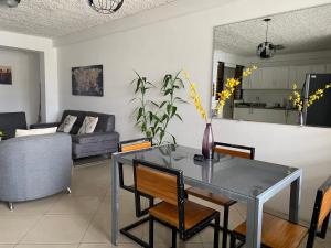 聖何塞的住宿－7 De Marzo Sabana，客厅配有玻璃桌和椅子
