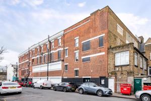a brick building with cars parked in a parking lot at Beautiful Flat Near the Center 11 min by tube in London