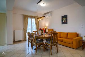 a dining room with a table and chairs and a couch at Luxury Villa King George in Nea Makri in Nea Makri