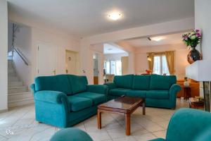 a living room with two blue couches and a table at Luxury Villa King George in Nea Makri in Nea Makri