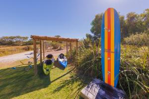 Duas pessoas estão sentadas num baloiço com uma prancha de surf. em Club Wyndham Dunsborough, Trademark Collection by Wyndham em Dunsborough