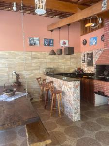 eine Küche mit einer Bar mit Hockern und einem Herd in der Unterkunft Pousada Villa Del Bosque - Chalé Familiare in Camanducaia