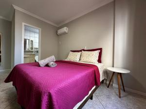 una camera da letto con un grande letto con una coperta rosa di NP01- 3 Quartos | Churrasqueira | Garagem a Itapema