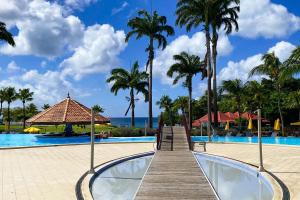 a resort pool with palm trees and a wooden boardwalk at PIERRE ET VACANCES Idéal Calme et Confort 2 à 4 personnes in Sainte-Luce