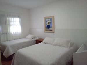 a bedroom with two beds and a window with a picture at Casa dos Neves in Campos do Jordão