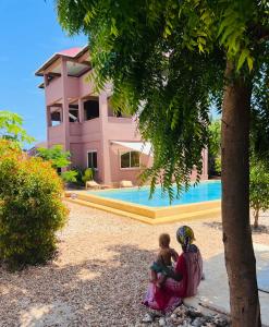 a woman sitting under a tree holding a child at Binta Boutique Hotel in Nungwi