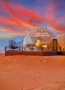 瓦迪拉姆的住宿－MARS LUXURY CAMP WADi RUM，海滩上的圆顶建筑,享有日落美景