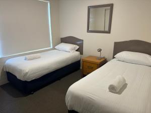 een hotelkamer met 2 bedden en een spiegel bij Baywatch 3 in Merimbula