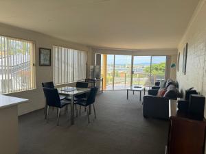 een woonkamer met een bank en een tafel en stoelen bij Baywatch 3 in Merimbula