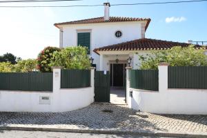 a white house with a fence in front of it at Casa vista Arrabida in Cotovia