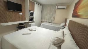 a small hotel room with a bed and a tv at Mar de Ponta Negra in Natal