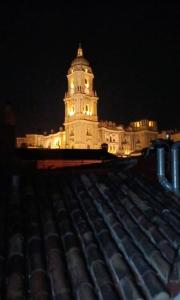 a large building with a clock tower at night at LUXURY APARTMENTS CHINITAS 11 in Málaga
