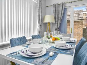 un comedor con una mesa con sillas azules y una ventana en Luxe 5 Bed Bungalow In Snodland, Medway, Kent en Kent