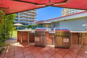 an outdoor kitchen with an umbrella on a patio at Vitina Studio Motel in Darwin