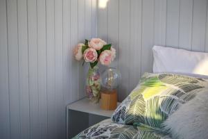 eine Vase mit Blumen auf einem Tisch neben einem Bett in der Unterkunft Taranaki Creekside KEA in Stratford