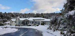 ein Haus ist mit Schnee bedeckt mit einer Auffahrt in der Unterkunft Taranaki Creekside KEA in Stratford