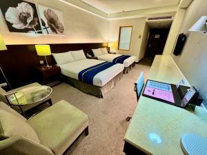 Habitación de hotel con 2 camas y escritorio con ordenador portátil. en HiYesHotel勤天商旅-花蓮館, en Hualien City