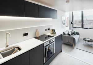 a kitchen with black cabinets and a living room at Central Manchester Duplex - Balcony - Roof Terrace - Parking in Manchester