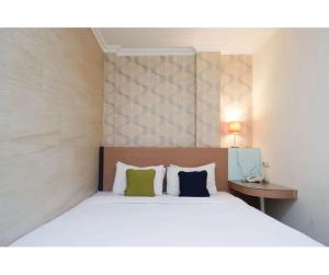 una camera da letto con un grande letto bianco con due cuscini di Capital Hotel Makassar a Pampang