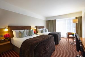 a hotel room with two beds and a desk and a room at The Croke Park Hotel in Dublin